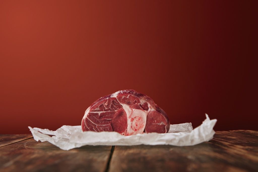 presentation-raw-angus-leg-steak-white-craft-paper-wooden-table-red-background.jpg